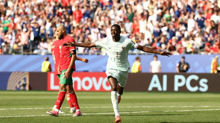 Ousmane Dembélé célèbre son but contre le Maroc à la Coupe du Monde 2026, avec un supporter marocain dépité derrière lui et des panneaux publicitaires